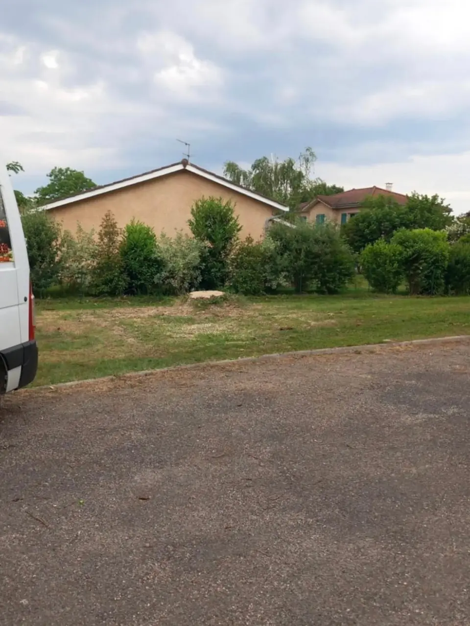 Le terrain dégagé devant la maison, la souche coupée au ras de la pelouse.
